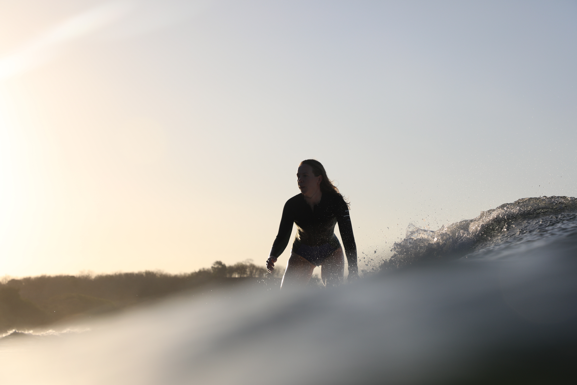 Silhouette of a surfer riding a wave at sunset